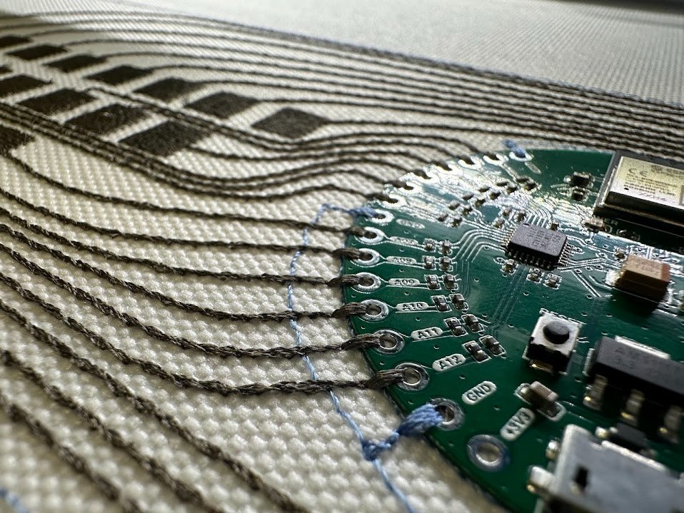 Circuit board with conductive traces stitched into woven fabric